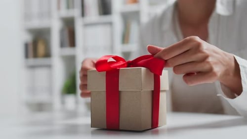 Woman Unpacking Gift with Red Ribbon