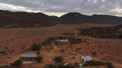 Aerial pulls out from small group of homes in inhospitable desert sand