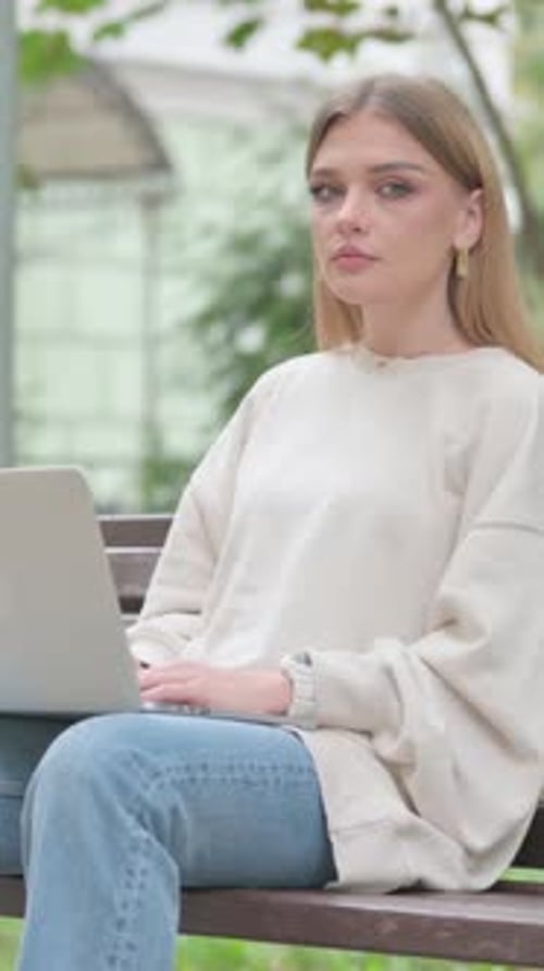 Woman Works on Laptop on Park Bench