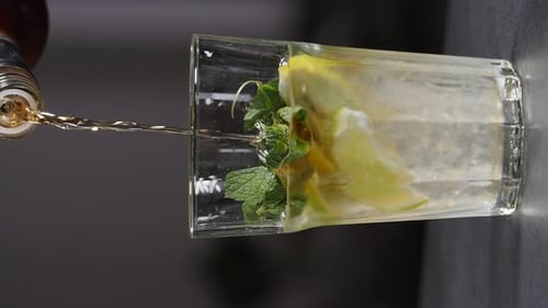 Pouring Rum into Refreshing Mojito with Mint and Lime