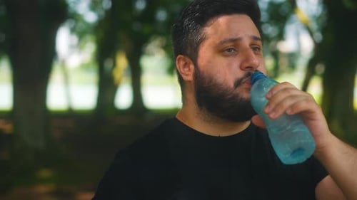 Portrait orbital close up shot man drinking water after workout outdoors
