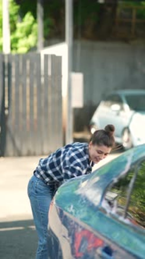 Engaged at the Car Wash a Lovely Young Lady is Washing Her Car with a Sponge and Cleaning Solution