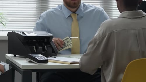 Manager Counting Paper Cash with Machine while Meeting with Client in Bank