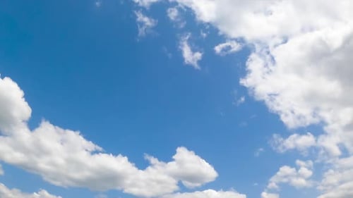 Azure summer sky with white fluffy clouds. Soft cloudscape in the atmosphere. Low angle view.