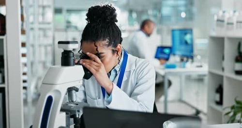 Young Woman Using Microscope in Bright Laboratory