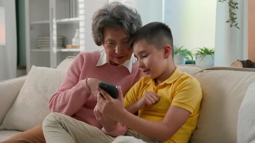 Grandmother and Child Using Mobile Phone Together Indoors