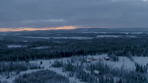 Aerial view quiet dawn secluded wintry rural snow covered cabins surrounded by Scandinavian woodland