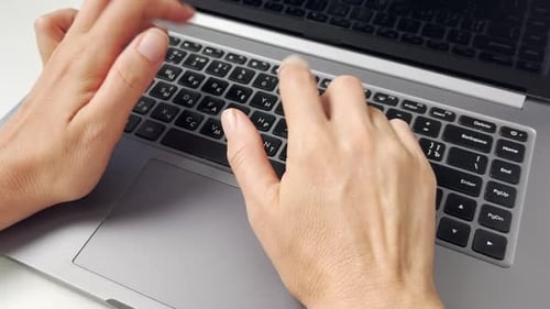 Hands Typing on Laptop Keyboard in Office