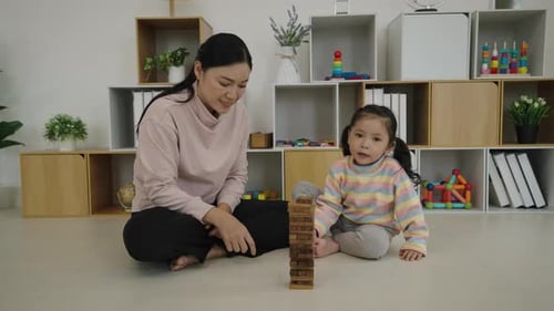 happy toddler girl with mother playing wooden block toy together