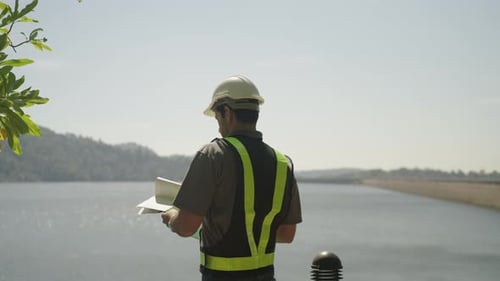 Blue collar worker is working at the dam.