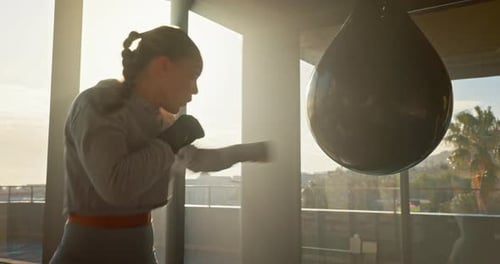 Woman Training with Punching Bag in Bright Gym