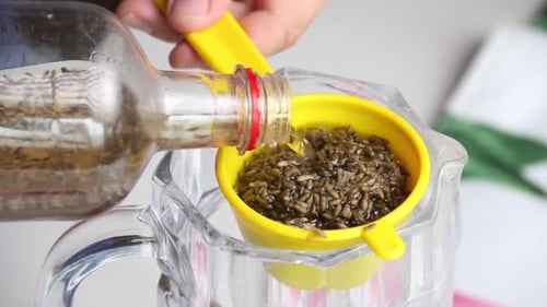 Um homem filtra vodka com infusão de flores de lavanda. Passa por uma peneira para remover as flores