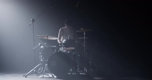 Man Fixing Earphone and Playing Beat on Drums
