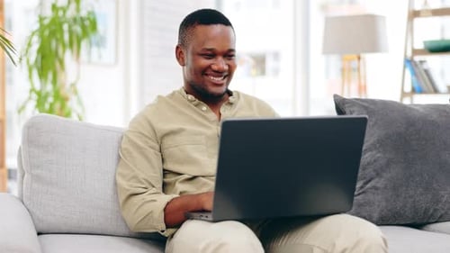 Young Adult Using Laptop on Couch Indoors
