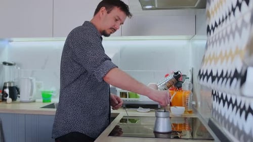 Wide Shot White Male Making Coffee on Stovetop in Modern Kitchen Patterned Backsplash Island and