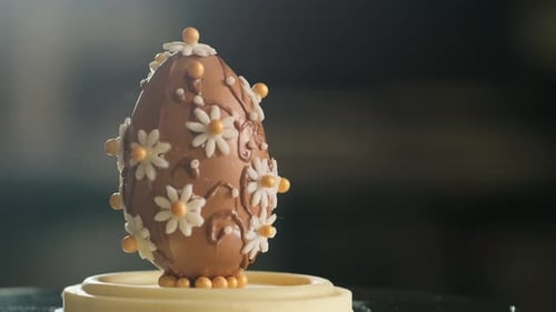 Chocolate Easter Egg Rotating on White Stand Isolated on Black