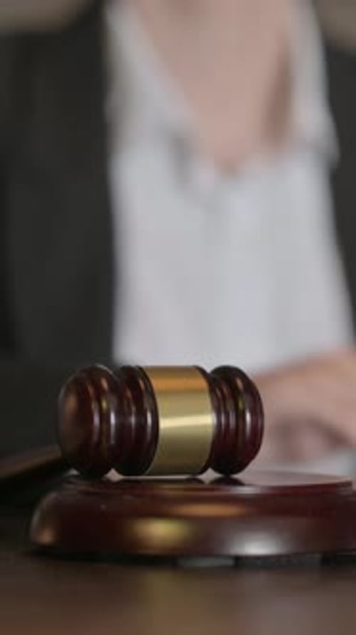Primer plano de una jueza golpeando un mazo para anunciar el veredicto, vertical
