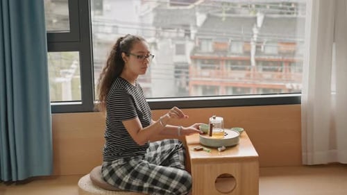 Passageira aproveita um momento para saborear comida e bebida fora do hotel Mulher sentada na janela do hotel
