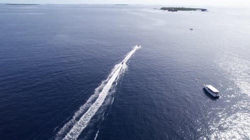 A Jet Ski Floats in the Ocean Along a Green Island