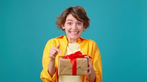 Cheerful Woman Holding Birthday Gift on Turquoise Background