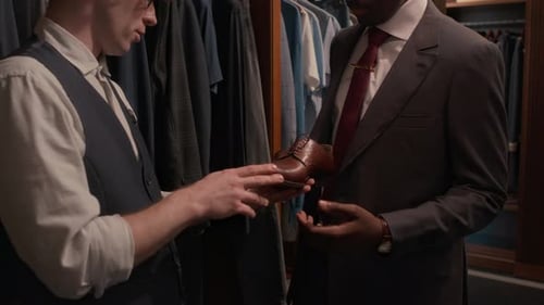Salesman Assisting Customer with Footwear Choice in Stylish Menswear Shop