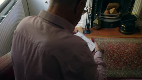A lonely senior man opening a debt letter. The mature male is reading a rent overdue final notice at