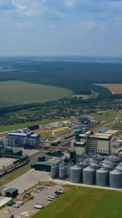 Innovative agriculture factory in nature. Modern grain silos elevators on green field in summer.