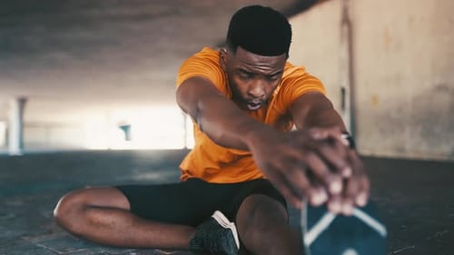 Man Stretches Leg Muscles in Urban Setting