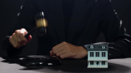 Gavel Strikes Next to Miniature House Model