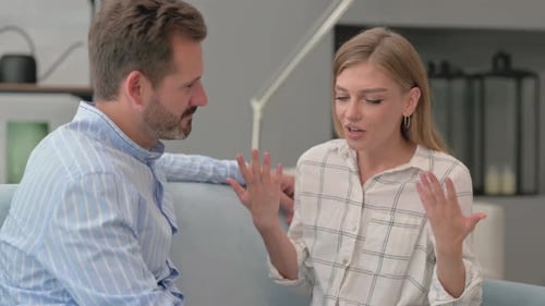 Man and Woman Talking on Sofa Indoors