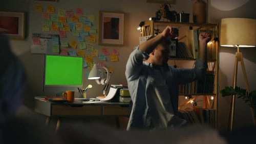 Man celebrates success in front of computer with green screen
