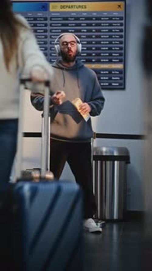 Crowded Airport Terminal Man in Headphones Eating Snacks Waiting for Flight in Boarding Lounge
