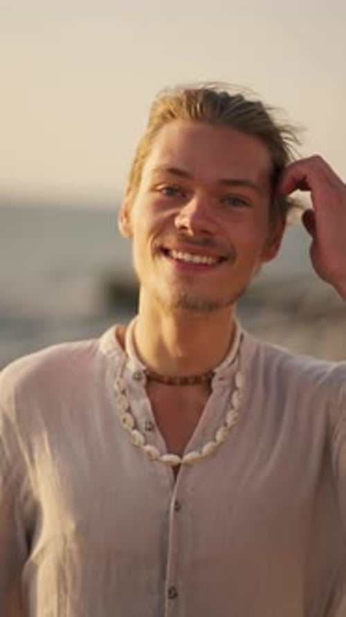 Smiling Young Adult Man with Shell Necklace on Beach