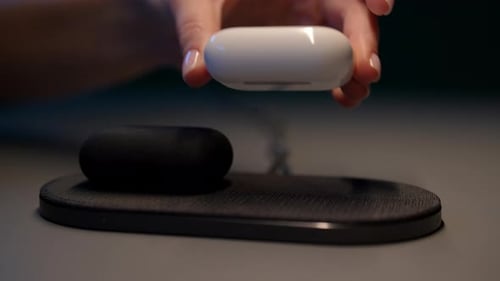 Hand Placing White Earbud Case on Charger