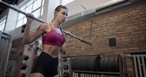 Young Beautiful Woman in Sportswear Doing Workout and Squat Exercises for Legs with Barbell in the