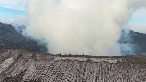 People hiking on the smoking bromo volcano crater rim in indonesia