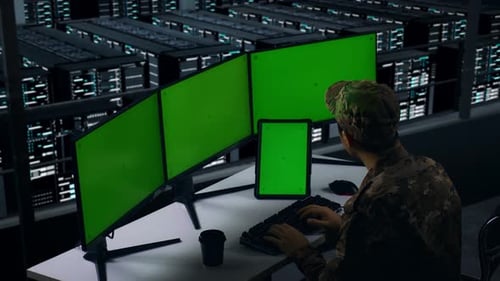 Military Working With Tablet And Computer Monitor With Mock Up Green Screen In Data Center