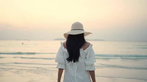 4K Young Asian woman walking on tropical island beach at summer sunset