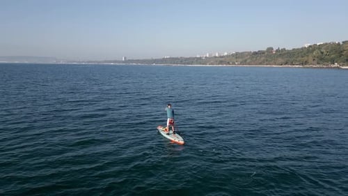 Aerial View of a Man Paddling a Standup Paddleboard or SUP Board on a Calm Sea