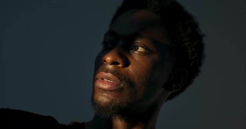 Dark Skined Male Young Man Looking at Bright Light Standing in Studio Isolated Playing with