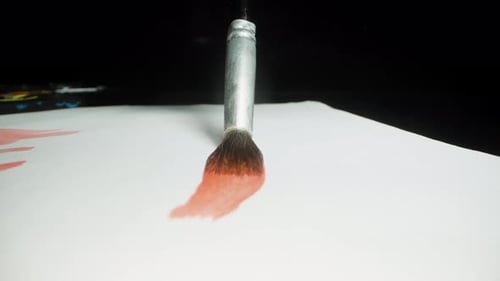 The camera follows the red line drawn by the brush on the paper. Dolly slider extreme close-up.