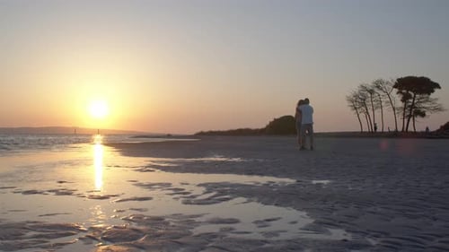 Romantic couple hugging in front of amazing sunset at beach honeymoon, day