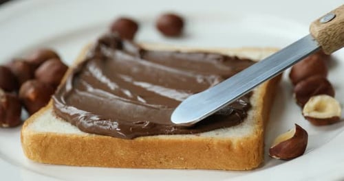Chocolate Spread on Toast with Hazelnuts on Plate