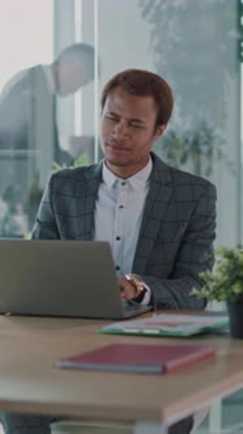 A Professional Businessman Engaged in Focused Work on Laptop Within a Modern Office Environment