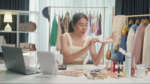 Asia lady vlogger looking at camera recording swatch apply new collection lipstick on arm show.