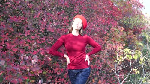 Young Beautiful Sensual Woman in a Red Sweater and Beret Posing in the Autumn Forest Against a