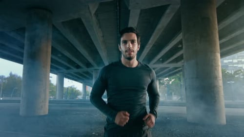Close Up Shot of a Tired Athletic Muscular Young Man in Sports Outfit Jogging in the Street. He is