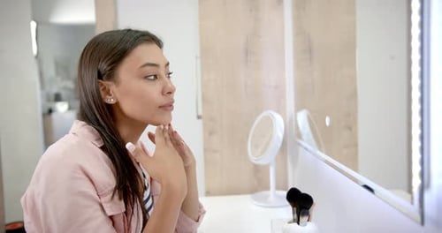 Woman Examines Her Face in Lit Vanity Mirror