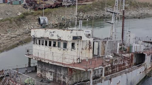 Rostgraues, halb untergetauchtes Schiffswrack, das an einem bewölkten, bewölkten Tag in Küstennähe vor Anker lag. Langsamer Dolly-Eiter