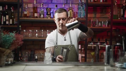 Stylish Bartender Making Cocktail in Red-Lit Bar